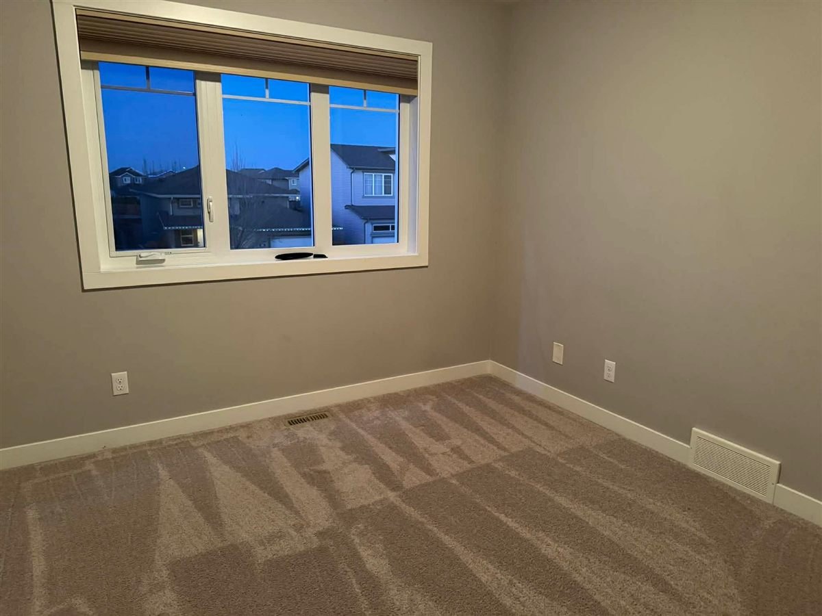 Empty bedroom with vacuumed carpet and a window