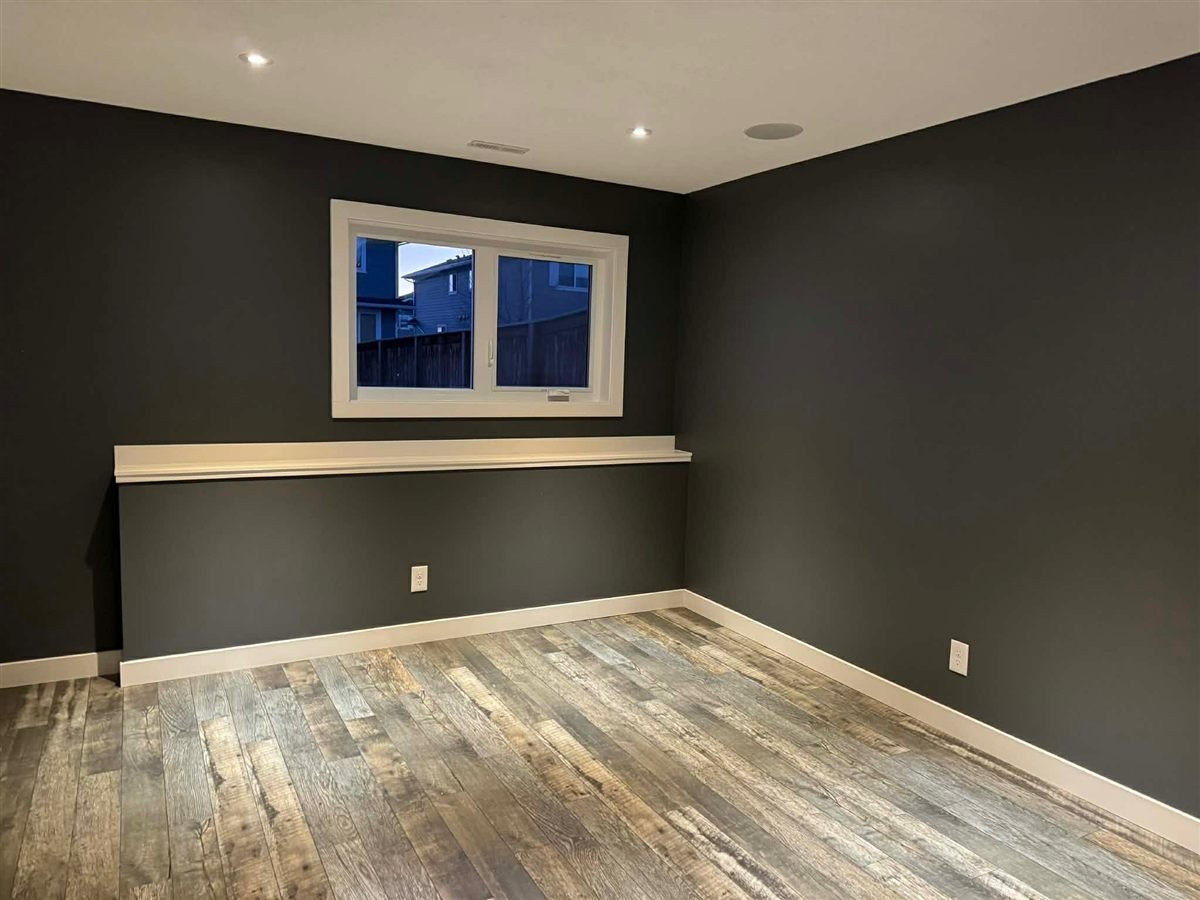 Room with dark walls, wood-look floor and a window