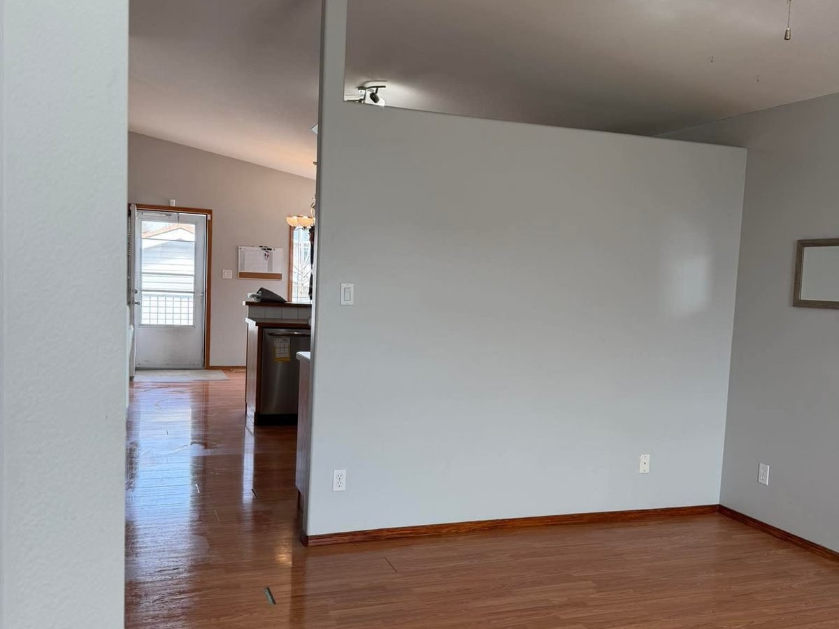 Hallway and room with a polished hardwood floor