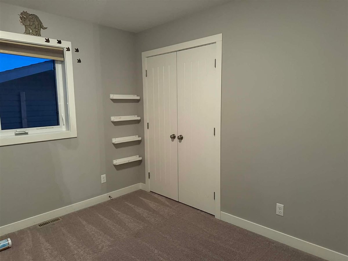 Bedroom with closet doors, wall shelves and a window